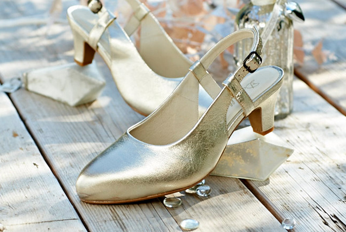 A pair of gold dress shoes on a wooden table