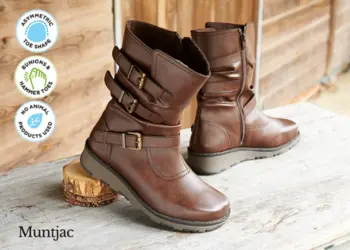 A pair of brown boots with straps on a wooden table