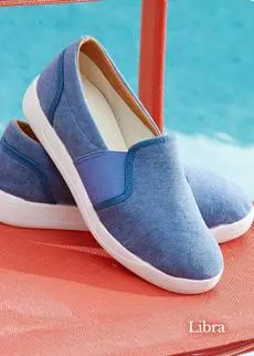 A pair of blue canvas shoes on a chair next to a pool.
