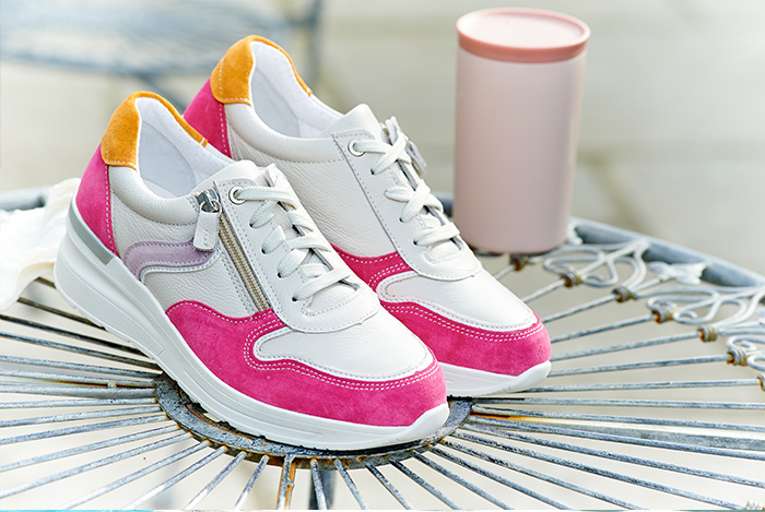 A pair of white and pink trainers on a table