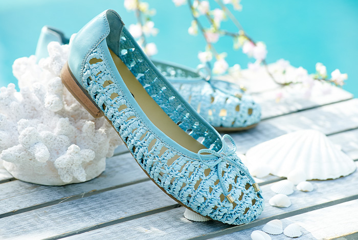 A pair of blue raffia material loafers on a table
