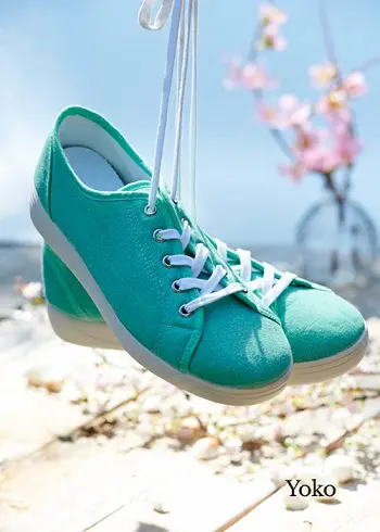 A pair of green canvas shoes hanging above a beach