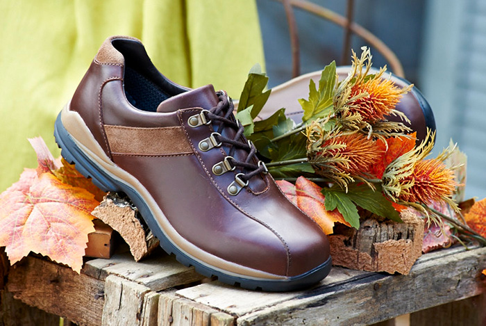 A brown walking shoe on a table next to a bunch of flowers