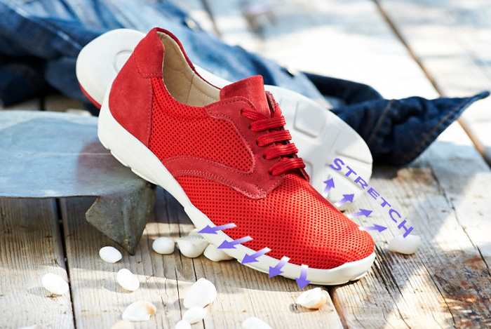 A pair of red laced trainers with a stretch icon overlaid