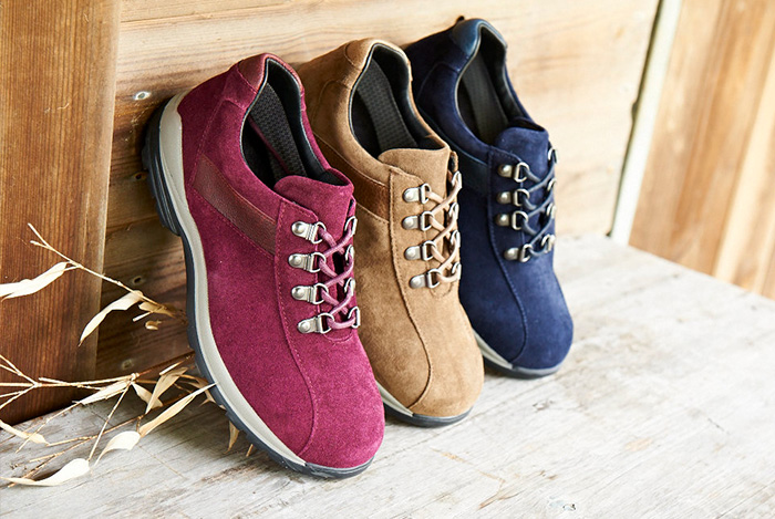 A trio of women's walking shoes against a wall