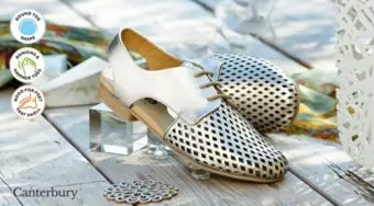 A pair of gold lace up shoes with a punched desgn
