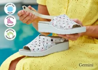 A woman holding a pair of white wedge sandals