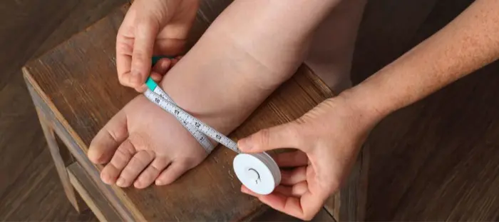 A person measuring aroud their left foot