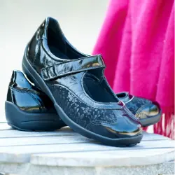 A pair of black womens strap shoes on a table