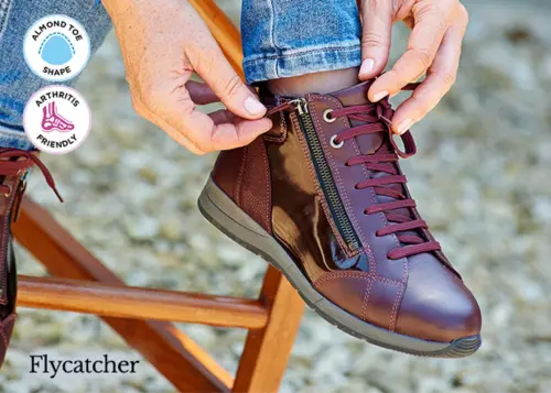A woman putting on a burgundy trainer