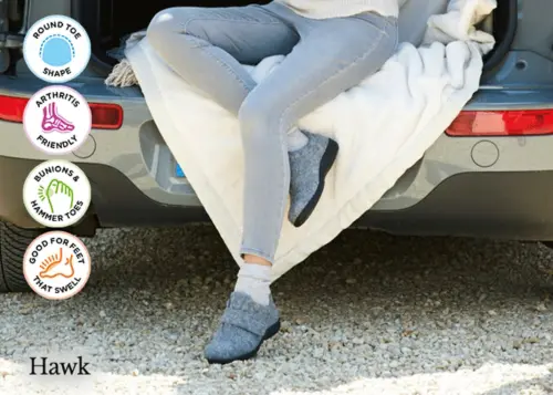 A woman sat in a chair wearing grey slippers