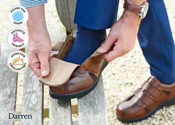 A man opening the strap on his brown shoes