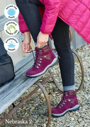 A woman lacing up purple walking boots