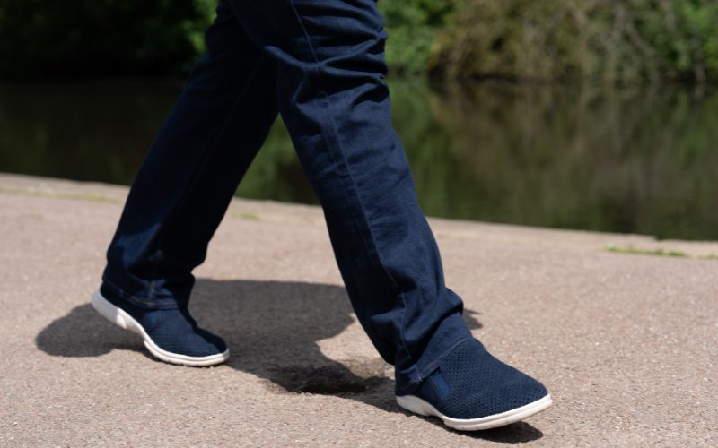 Someone walking in a pair of jeans and blue canvas shoes