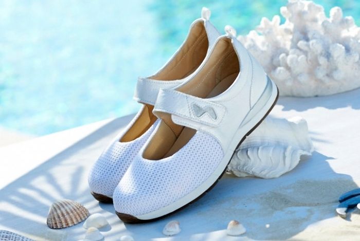 A pair of white strap shoes in the sun on a table