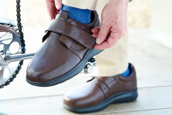 Someone putting on a pair of brown strap shoes