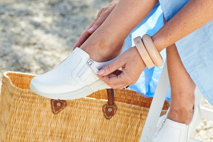 Someone zipping up a pair of white trainers