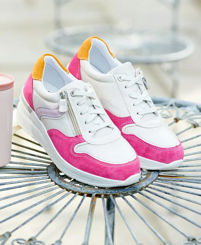 A pair of pink and white trainers on a table