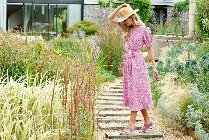 A woman in a pink dress standing in a garden