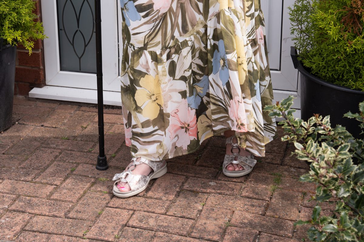 A woman with a walking stick and silver sandals