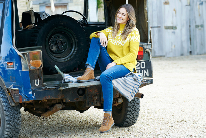 A woman sat on the tail gate of a land rover
