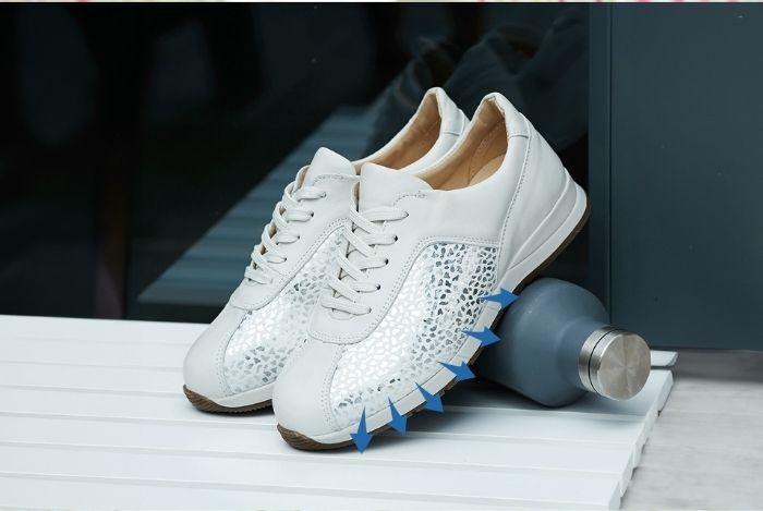 A pair of white trainers on a table and water bottle