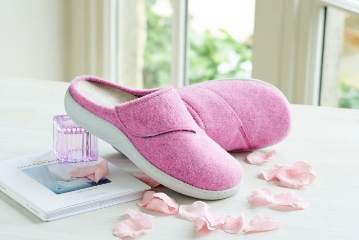 A pair of pink sliders on a table with rose petals