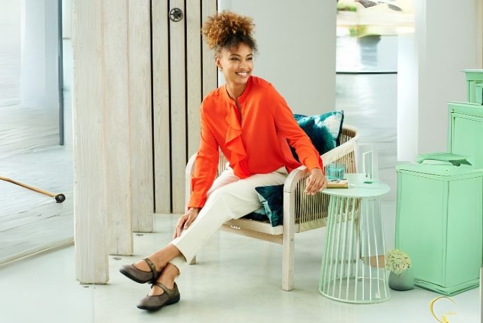 A woman sat in a chair with an orange shirt