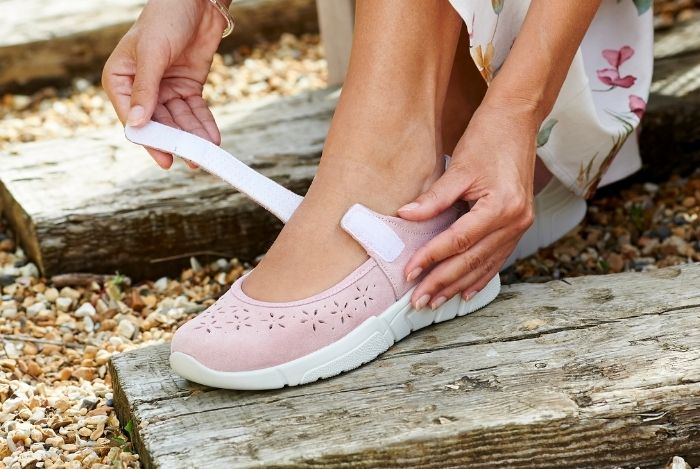 Someone strapping up a pair of shoes on a wooden block