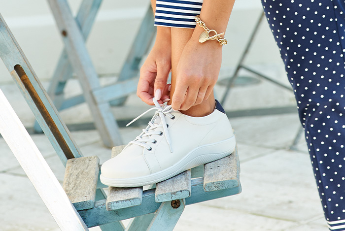 Someone tying up a pair of white shoes on a step
