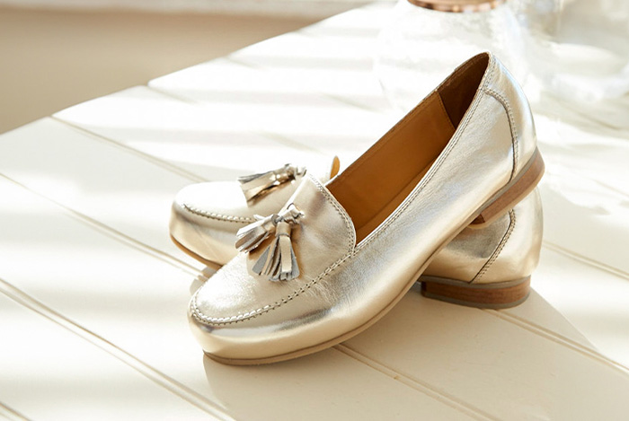 A pair of gold loafer shoes on a wooden table