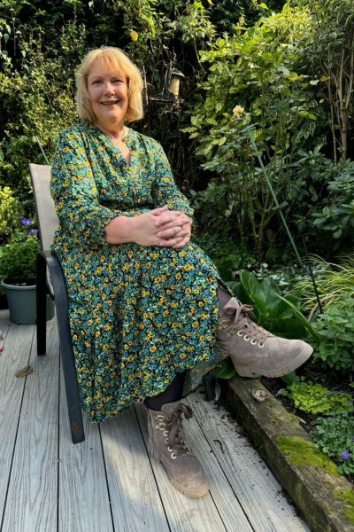 A woman sat in her garden in a green dress