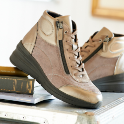A pair of gold lace up and zip boots on some books
