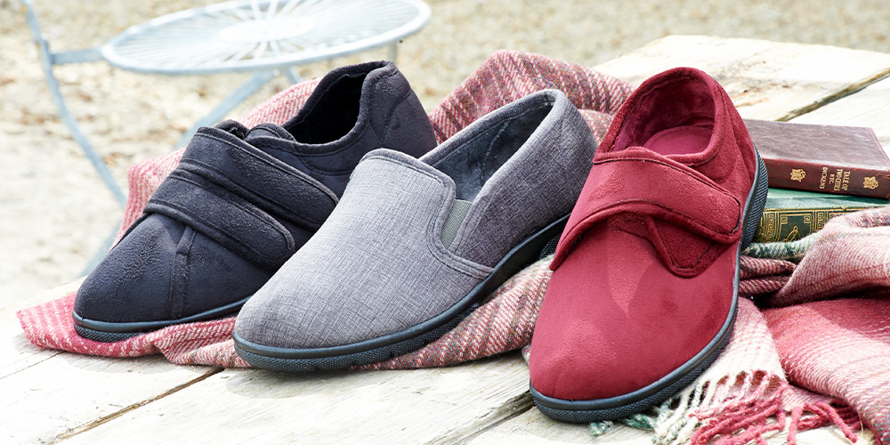 A trio of different coloured slippers on a wooden bench