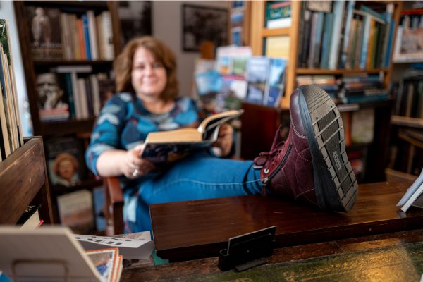 A woman sat in a chair reading with her feet up on a table