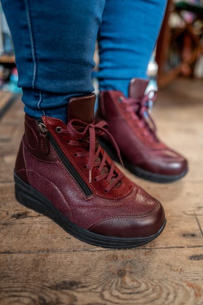 Someone in blue jeans and burgundy boots