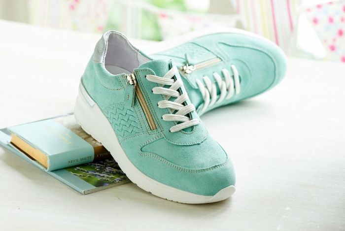 A pair of light green lace up trainers on a table