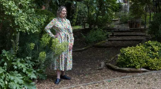 A woman in a floral dress standing amongst some foliage