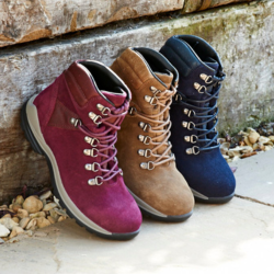 A trio of different coloured walking boots leaning against a wall